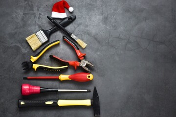 Creative Christmas tree made of construction tools on a gray background with santa claus hat....