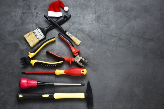 Creative Christmas tree made of construction tools on a gray background with santa claus hat. Industrial greeting card and happy new year creative concept.