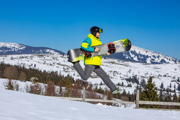 man jumping with snowboard in hands mountains on background