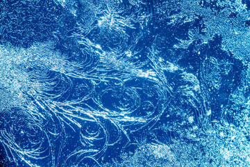 Beautiful blue frost patterns on frozen window as a symbol of Christmas wonder. Christmas or New year background.