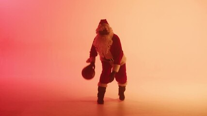 Santa Claus playing basketball on red background. African american man in costume of Santa, holding ball, doing sports. New year time and christmas holidays concept.