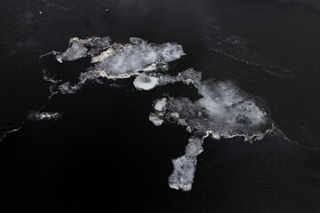 Pieces of thin white ice on dark water. Melting ice in the spring. Global warming.