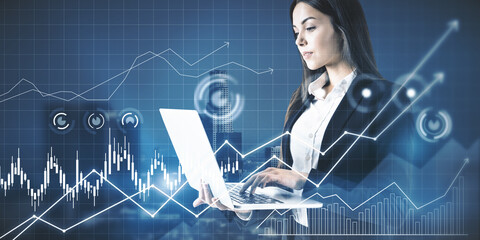 Attractive young european businesswoman using laptop computer with glowing business chart grid on blurry city background. Finance and technology concept. Double exposure.