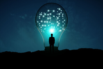 Back view of backlit man looking at creative glowing lamp with polygonal connections on night landscape background. Idea and innovation concept.
