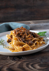Ragout with pasta on a plate cooked with braised duck breast, root vegetables, tomatoes and herbs