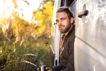 Portrait of a man sitting in the doorway of his camper van 