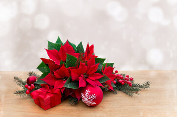 Christmas decoration. Flowers of red poinsettia, christmas tree, red balls, gift box on table on a...
