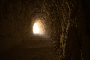 exit light in the end of a deep dark tunnel carved in stone