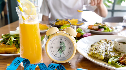 Selective focus of  yellow Alarm clock limit time of eating healthy food consumption Diet to Lose weight concept