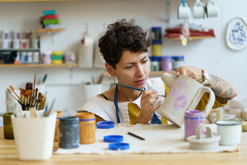 Young creative woman small business owner work in art studio with pottery for handmade shop. Girl...