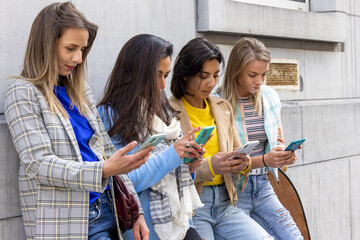 Multiracial group of teenagers have fun playing happily with smartphones. Use by millennials of cell phones and social applications. . High quality photo