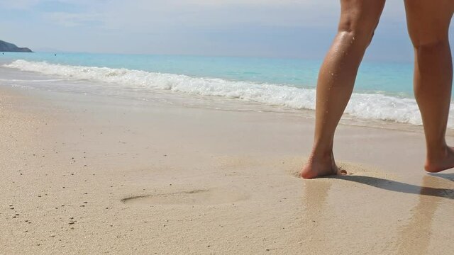 woman legs walking by sandy sea beach