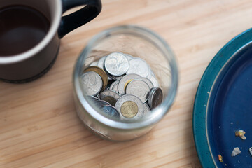 Canadian toonie loonie and quarter money in jar on a desk
