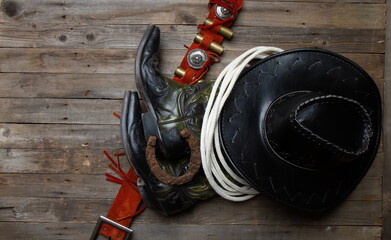 leather classic cowboy hat with lasso and horseshoe on rough wooden table