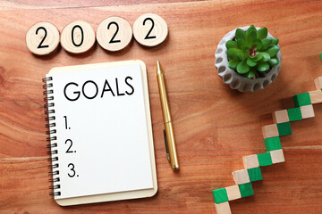 Business concept of top view 2022 goals list with notebook over wooden desk