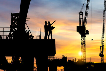 Silhouette of Engineer and worker checking project at heavy infrastructure building site...