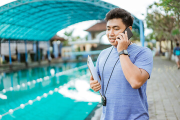 a swimming coach makes a phone call using a smartphone
