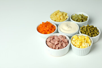 Bowls with Olivier salad ingredients on white background