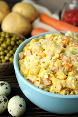 Olivier salad and ingredients on wooden background