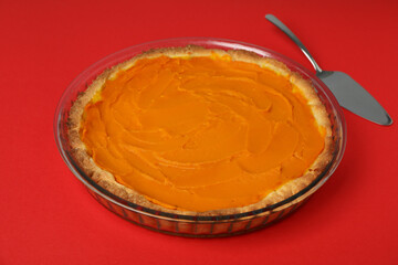 Pumpkin pie and cake spatula on red background