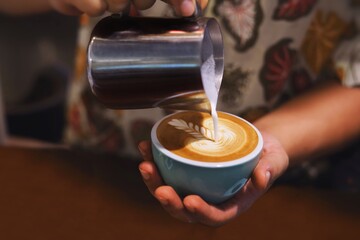 Close up barista hands making coffee latte art,Barista pouring milk in coffee mug for making latte art at cafe
