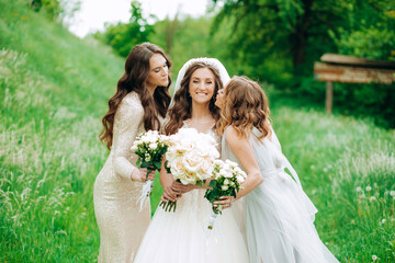 Two bridesmaids kiss her on the cheeks on both sides.