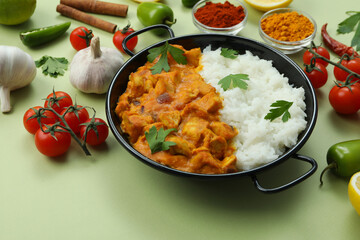 Chicken tikka with ingredients on green background