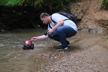 A man is holding a radio-controlled car in his hands.Hobby, fun sport. Radio controlled model car, trophy crossing. 