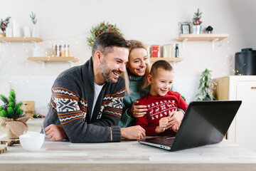 Family man woman and little son having fun shopping online using laptop, choosing gifts for Christmas and New Year