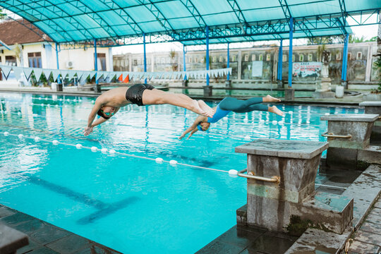 male and female athlete jumping position while plunging into the pool after cue