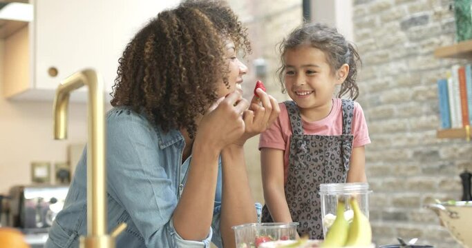 Mum and daughter having fun making a silly face with strawberries