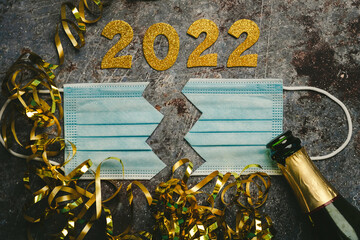 New Years Eve celebration concept background.Protective surgical mask split in two with the numbers 2021 and Champagne bottle. Concept of end of Covid19 pandemic