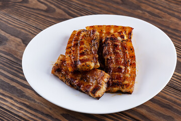 Grilled bacon on a white plate.