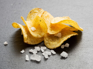 potato chips with salt on slate background