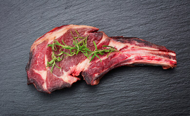 dry-aged raw tomahawk steak on slate background
