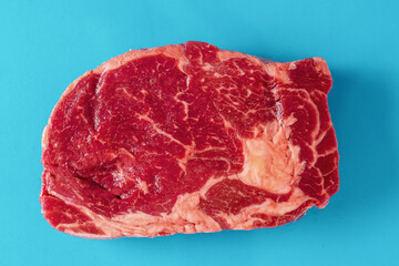 Fresh juicy rib eye steak on blue surface. Top quality fresh meat. Butcher craft product and meat industry. Rich red color and marbling. Premium cut.