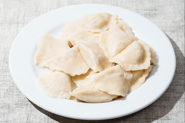 Serving of traditional Polish pierogy dish on a white plate. Dumplings filled with meat, cheese and mushrooms. Popular Eastern European food