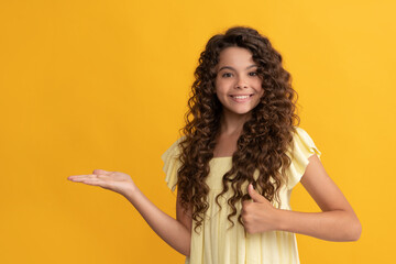 happy kid with long curly hair and skin presenting product show thumb up, copy space, advertisement.