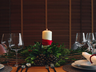 Beautiful table setting for Christmas dinner with candle and wreath