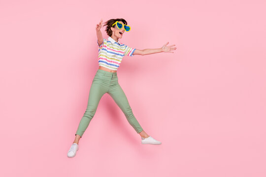 Full Body Profile Side Photo Of Young Girl Striped Top Open Arms Hug Invite Jump Up Sunglass Isolated Over Pink Color Background