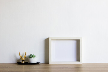 Fototapeta na wymiar White frame with cactus on a wooden table. 