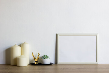 A white photo frame with candles and cactus on table. 