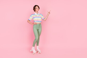 Full body photo of young girl happy smile roller skater point finger empty space ad choice isolated over pink color background