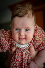a little baby girl in a colorful dress lies on a baby carrier