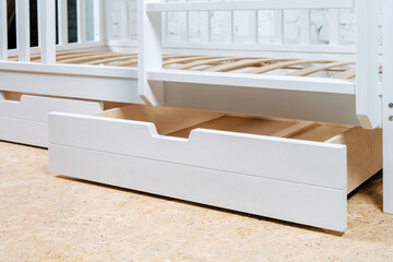 The image of the child's bed, bottom view of the storage drawers. White beautiful furniture.