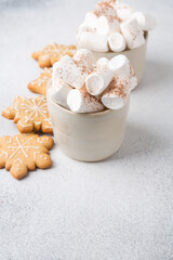 Two mugs of hot cocoa served with marshmallow on a gray background, copy space