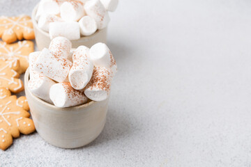 Two mugs of hot cocoa served with marshmallow on a gray background, copy space