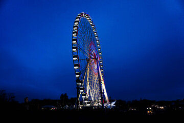 Fototapeta premium The attraction from an amusement park, a huge colorful wheel spinning in the dark