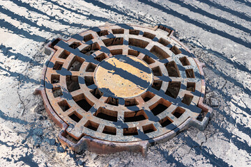 A cast-iron storm sewer hatch on the road before laying the asphalt pavement poured with bitumen. Drainage of rainwater from the road surface. Close-up.