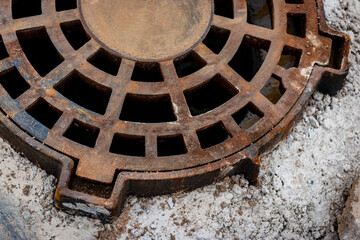 Cast-iron stormwater drainage hatch on the road before asphalt pavement. Drainage of rainwater from the road surface. Close-up.